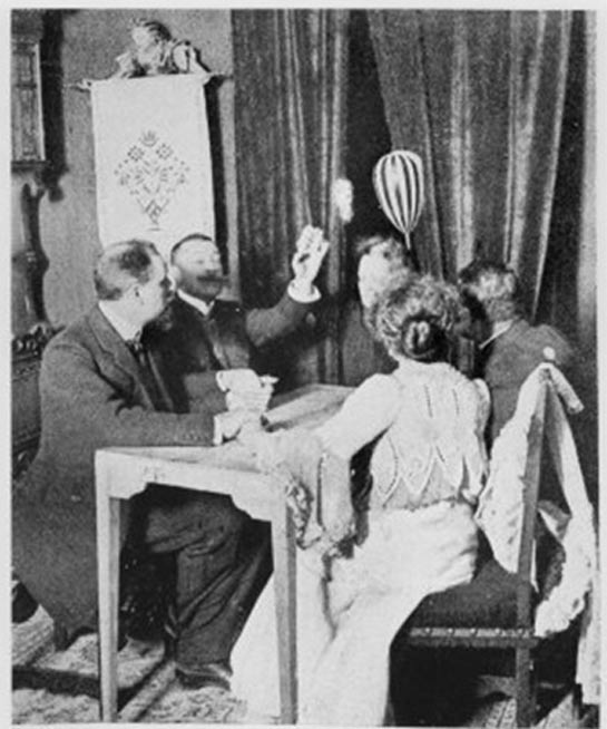 Die Mandoline (gestreiftes Instrument, oben rechts) schwebt über Palladinos Kopf vor den Vorhängen am hinteren Ende des Tisches während Palladinos Séance in München, Deutschland, 13. März 1903.