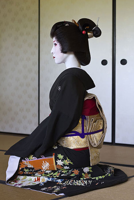 Profil der Miyagawa-chō geiko (Geisha) Kimiha in einem formellen schwarzen Kimono (kurotomesode) und einer Nihongami-Perücke im chū taka shimada-Stil.