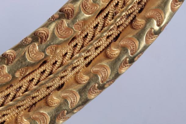 Detail der halbmondförmigen Prägung und des geflochtenen Golddrahtfrieses.