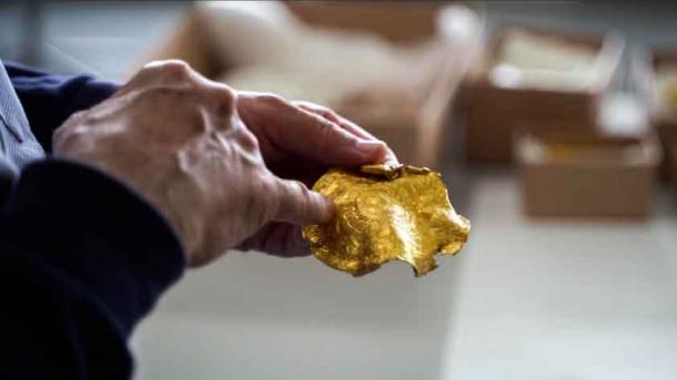 Ein Forscher untersucht einen Teil des Goldschatzes