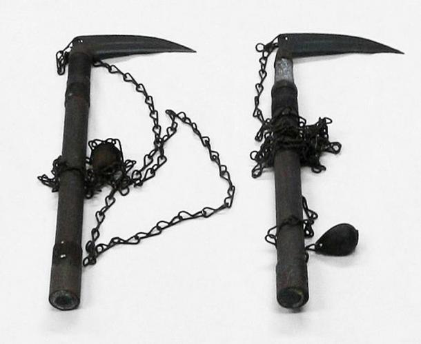 Ein Paar Kusarigama-Ninjawaffen, ausgestellt im Schloss Iwakuni. Kusarigama bestehen aus einer kama (dem japanischen Äquivalent einer Sichel oder eines Hakens) an einem kusari-fundo, einer Art Metallkette (kusari) mit einem schweren Eisengewicht (fundo) am Ende. Die Kusarigama soll während der Muromachi-Periode (1336-1573) in Japan entwickelt worden sein.