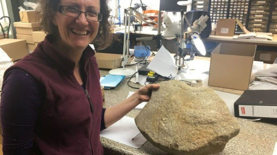 Dr. Ruth Shaffrey und der Mühlstein mit der römischen Phallusschnitzerei.