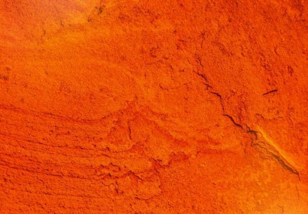 Eine rissige rotockerfarbene Wand, die antike Menschen in Nordchina in überschaubare Stücke zum Zerstoßen und Abrieb zerbrochen haben müssen