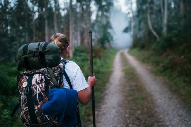 Rucksacktouristen, die auf dem Camino de Santiago in Spanien durch den Eukalyptuswald wandern.