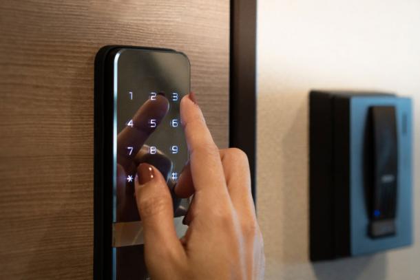 Nahaufnahme des Fingers einer Frau bei der Eingabe des Passwortcodes auf einem intelligenten digitalen Touchscreen-Tastenfeld für das Türschloss eines Hotelzimmers. 