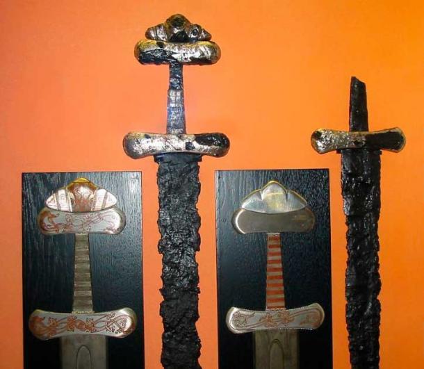 Zwei Wikingerschwertgriffe aus dem 10. Jahrhundert (Petersen Typ S) mit Intarsienverzierungen im Jelling-Stil neben ihren rekonstruierten Nachbildungen, ausgestellt im Wikingermuseum Hedeby.